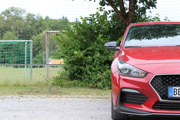 Nahaufnahme des Scheinwerfers eines roten Autos am Sportplatzrand