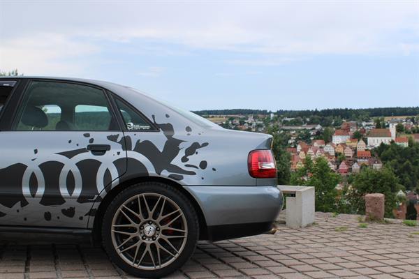 Auto mit Sticker auf der Motorhaube, im Hintergrund eine Kleinstadt