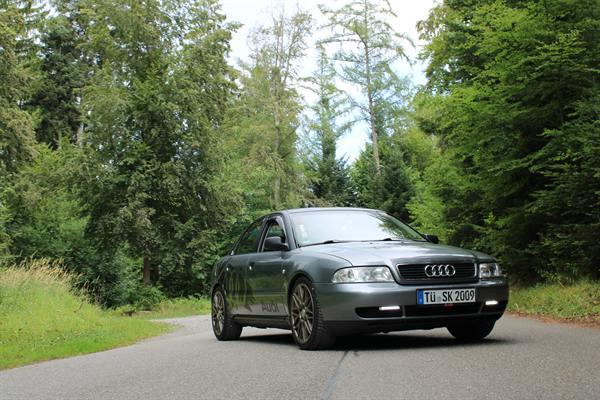 Silberner Audi auf einer von Bäumen gesäumten Straße