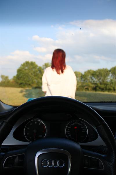 Blick durch die Windschutzscheibe auf eine Frau, die im Feld steht