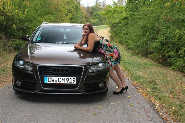 Frau im Blumenkleid lehnt sich an das Autofenster